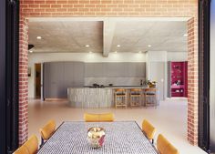 an open kitchen and dining room area with brick walls, floor to ceiling windows, and white tiled floors