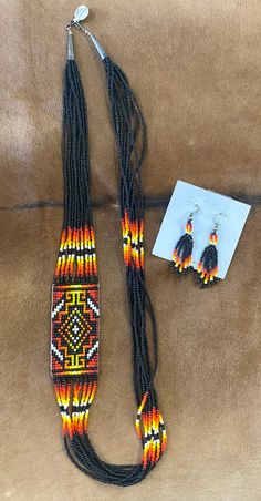 Authentic sterling silver Native made black beaded Aztec jewelry set. Featuring matching necklace and earrings. Aztec black, red, orange, & yellow strand necklace measures 28” inches length. Colorful fringed bottom handmade beaded earrings 2.5” inches length. Both of these beauties are Sterling silver. This set would make for a beautiful gift to a loved one or yourself. 😉 Traditional Orange Jewelry With Black Beads, Orange Dangle Jewelry With Black Beads, Handmade Southwestern Black Beaded Necklace, Handmade Rectangular Orange Jewelry, Handmade Orange Rectangular Jewelry, Handmade Southwestern Black Beads, Southwestern Style Black Beads As Gifts, Traditional Black Multi-strand Jewelry, Southwestern Style Black Beads Jewelry For Gift