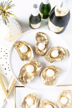 there are four pieces of gold foil on the plate next to two bottles of champagne