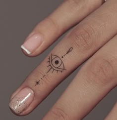 a woman's hand with a small tattoo on her left thumb and an eye in the middle