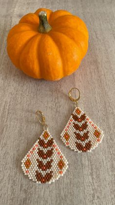 a pair of beaded earrings sitting next to a pumpkin