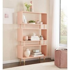 a pink shelf with books and vases on it