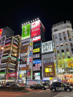 a busy city street at night with lots of tall buildings and cars driving on the road