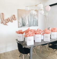 there are many bags on the table with pink bows and balloons in front of them