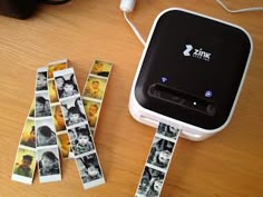 several polaroid tapes are placed next to an electronic device with pictures on it and the cord is plugged in