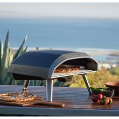 an outdoor pizza oven sitting on top of a wooden table