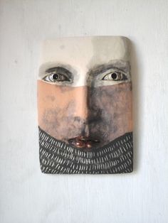 a face made out of paper with eyes and beard on the wall above it is an image of a man's face