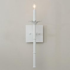 a white wall light with a single candle on it's side and two lights in the middle