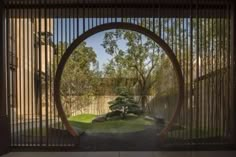 an open gate with trees and bushes in the background, through which is a circular window