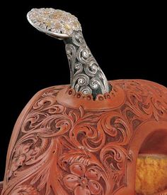 an intricately carved pumpkin with a silver plate on top