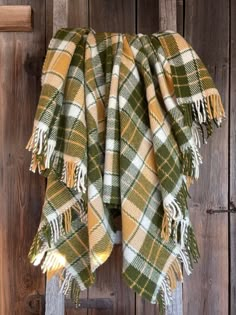 a green and yellow plaid blanket hanging on a wooden door