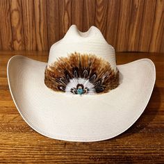 AU-FHB-02 Feather Hat Band for Cowboy Hats Beautiful Natural Feather Hat Band with Crown and Turquoise Stone Cluster center. Handmade from all natural feathers. Natural and Brown Feathers The height at the crown varies with the feathers and is approximately 3-1/4 inches. The band varies with the feathers and is approximately 1-1/2 inches. One size fits most. Brown Leather Tie Fastener. This hatband is handmade from natural feathers therefore the height, design and colors may vary slightly from w Hat Bands Western, Cowboy Hat Feather, Hat Design Ideas, Feather Hat Band, Horse Bedroom, Collage Supplies, Kimberly Brown, Cowboy Hat Bands, Urban Cowboy