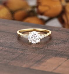 an engagement ring with three stones on it sitting on top of a wooden table next to stuffed animals