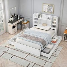 a white bed sitting on top of a wooden floor next to a desk and chair