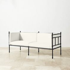 a black and white couch sitting on top of a tiled floor next to a wall