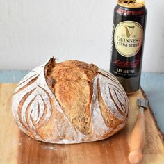 a loaf of bread sitting on top of a wooden cutting board next to a beer