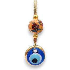 an evil eye charm hanging from a gold plated necklace with blue and orange glass beads