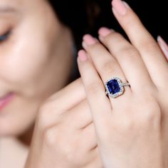 a woman wearing an engagement ring with a blue stone