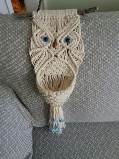 an owl purse is hanging on the back of a couch with blue eyes and tassels