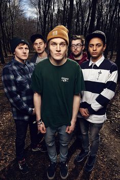 a group of young men standing next to each other in front of trees and dirt ground