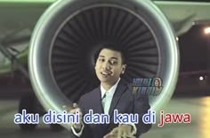 a man standing in front of an airplane with the words aku disini dan kau di jawa