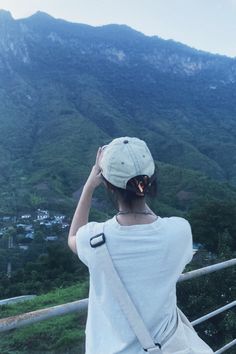 a woman standing on top of a bridge looking at the mountains