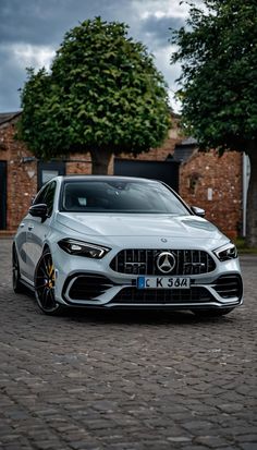 the front end of a white car parked on a cobblestone road