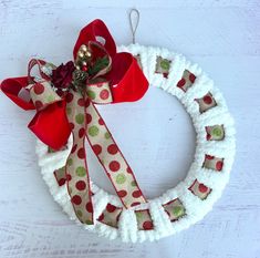 a white wreath with red and green polka dot ribbon hanging on a door hanger