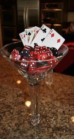 a martini glass filled with dice and playing cards on top of a counter next to a stove