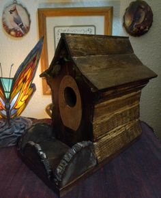 a wooden birdhouse sitting on top of a table next to a lamp and pictures