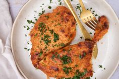 two pieces of chicken on a plate with a fork