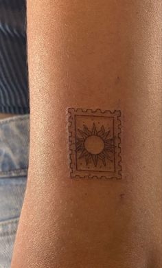 a person with a tattoo on their arm that has a stamp in the shape of a sun