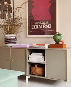 a sideboard with books, magazines and a vase on it in a living room