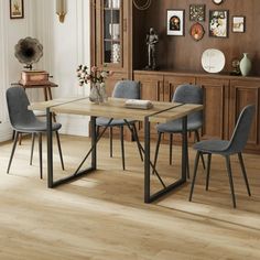 a dining table with four chairs and a bookcase in the corner next to it