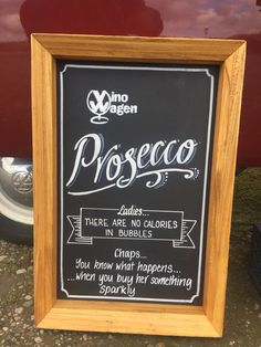 a chalkboard sign on the side of a red car that says proseco