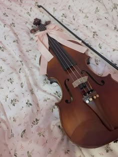 a violin laying on top of a bed next to a stick and flowered sheet