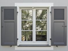 an open window with shutters on the outside and trees in the backround