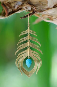 a close up of a gold necklace with a blue stone hanging from it's end