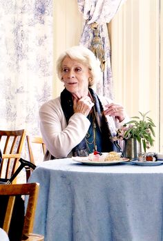 an older woman sitting at a table with food on it