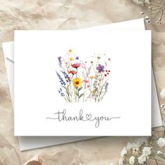 a thank card with wildflowers and the words, thank you written on it