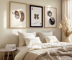 three framed pictures hang above a bed in a room with white linens and pillows