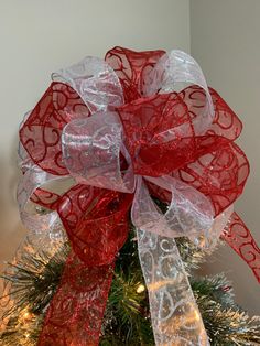 a red and white bow on top of a christmas tree