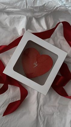 a red heart in a white box with a ribbon around it