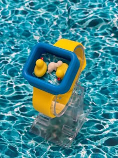 a rubber ducky floating in the water on top of a plastic stand with two rubber ducks