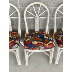 three white chairs with colorful upholstered cushions