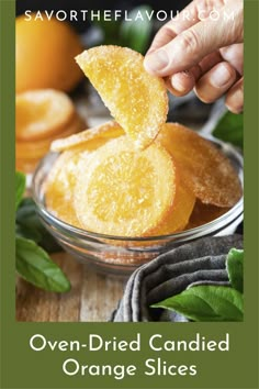 an orange slice being dipped with sugar in a glass bowl on top of a wooden table