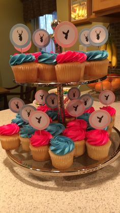 cupcakes on a cake stand decorated with blue and pink frosting