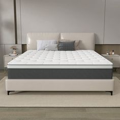 a white bed with no sheets on it in the middle of a room next to two nightstands