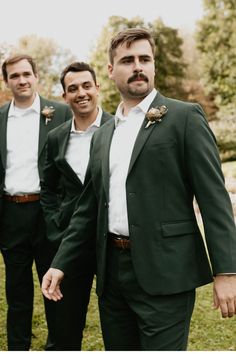 three men in tuxedos are posing for a photo together, one man is wearing a white shirt and the other wears a green suit