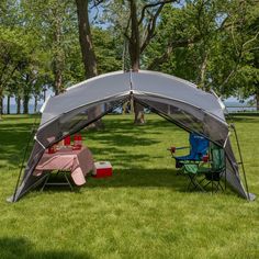 two lawn chairs are set up in the grass under a tent with an awning